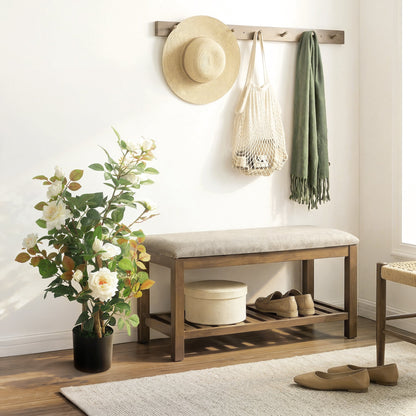 The artificial plant standing in a hallway next to a wooden bench with a hat and scarf
