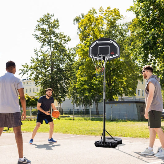 The basketball hoop and stand is set up on an outdoor court with three people playing basketball