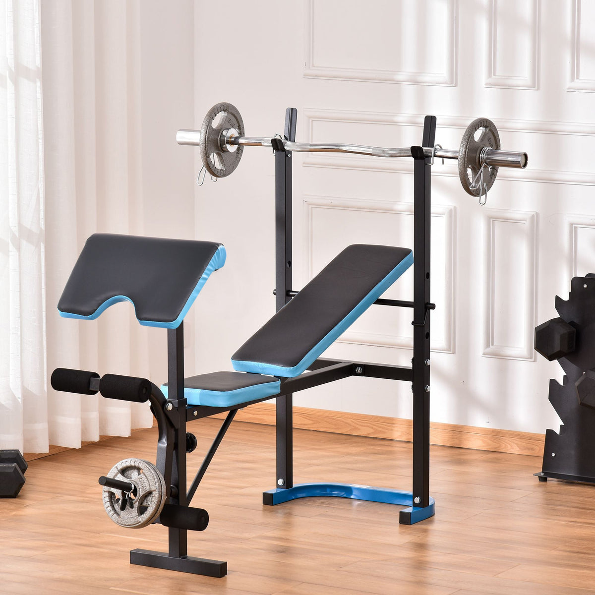 The weight bench set up in a home gym with a barbell and weight plates on the rack