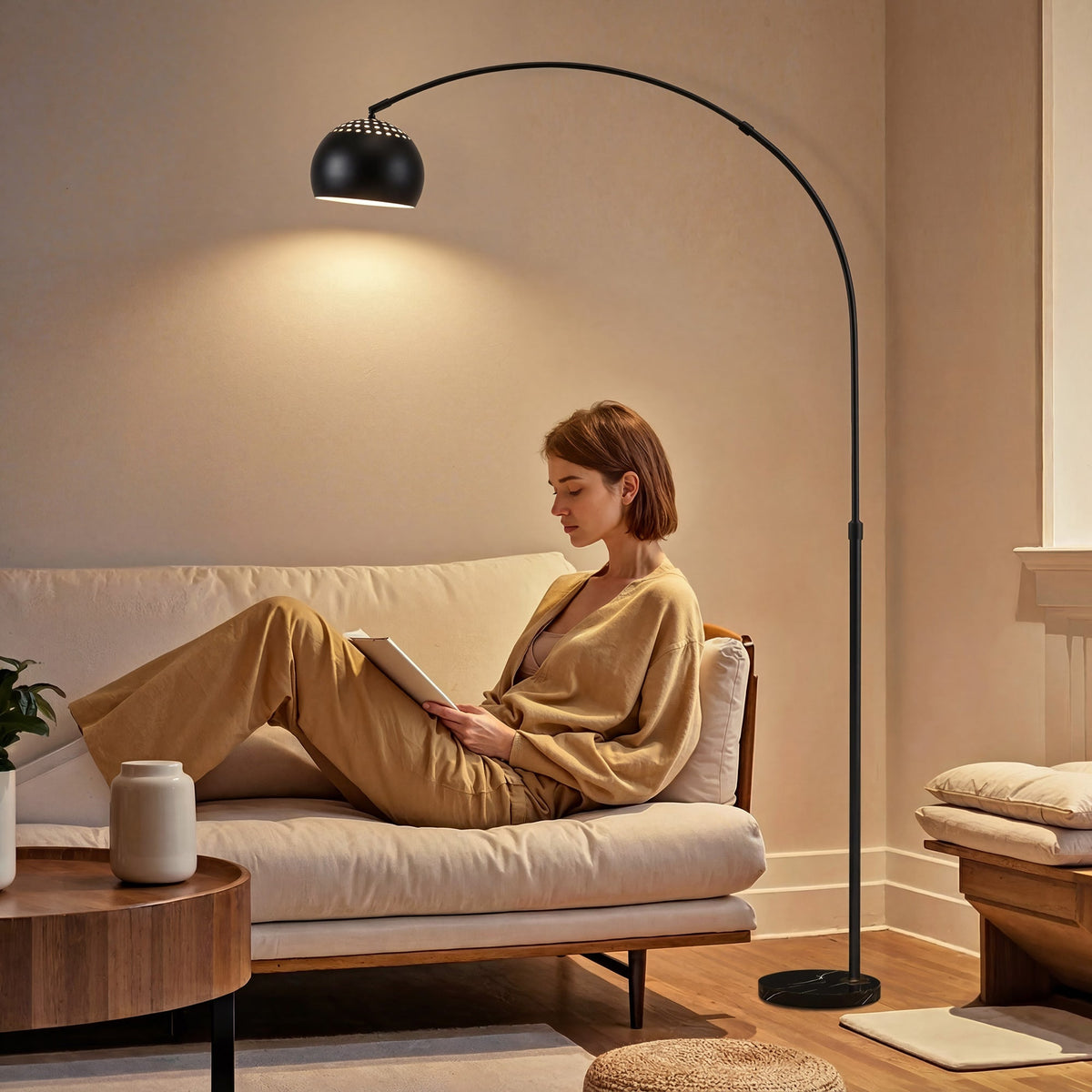 A woman reads a book next to the arc floor lamp in a modern living room