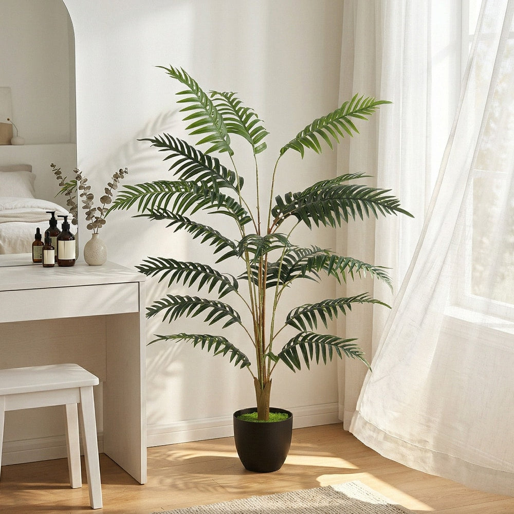 The artificial fern topiary tree placed in a bright room next to a desk and window