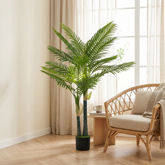 The artificial palm tree in a bright room next to a wicker chair and a small table