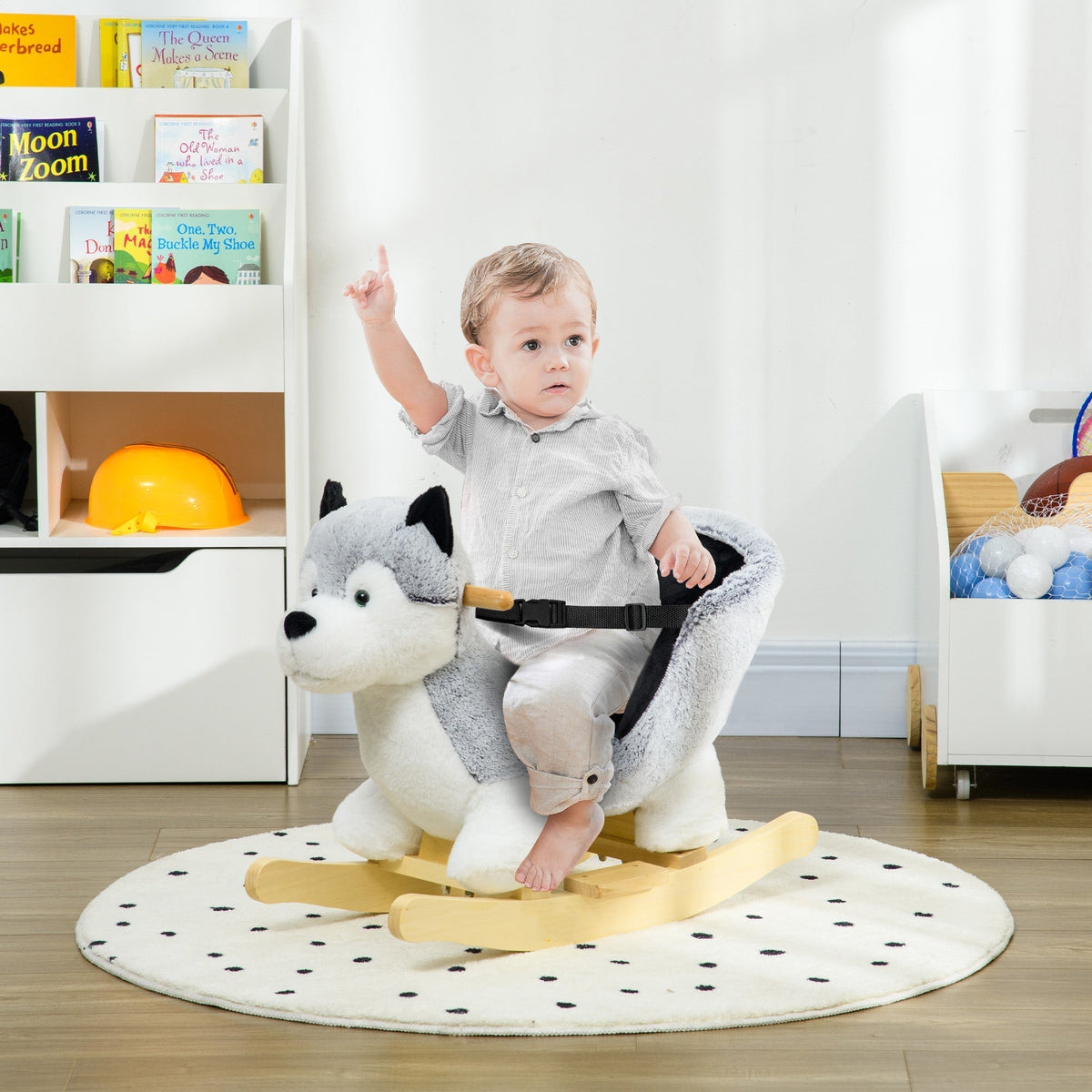A baby sits on the husky rocking animal, enjoying a ride on a rug