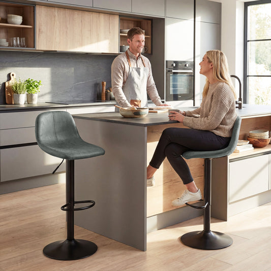 The green bar stools placed at a kitchen island with a couple sitting on them