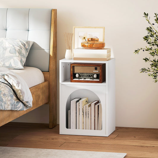 The white bedside table in a bedroom next to a bed, styled with books and a radio