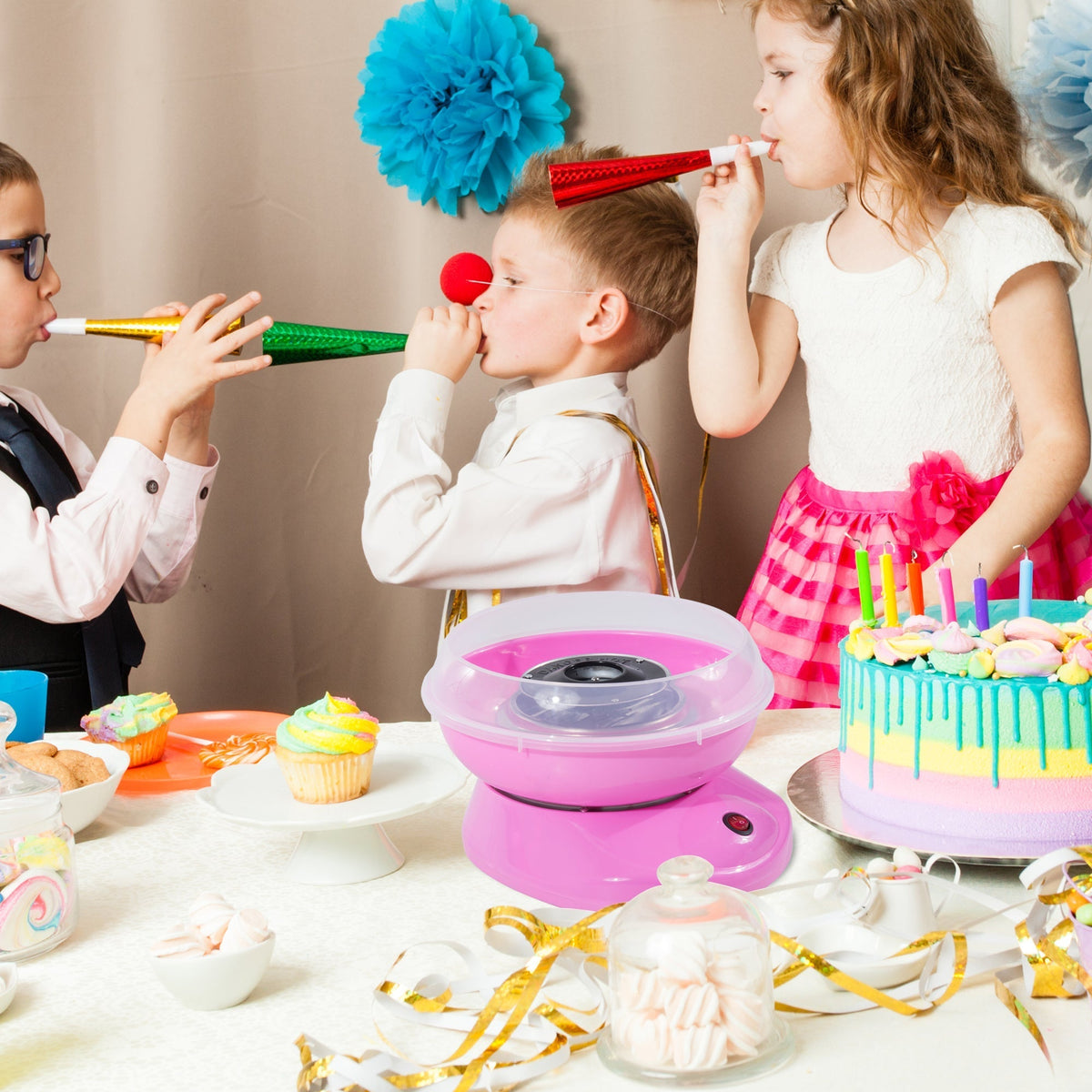 Children enjoying a party with the pink candy floss machine making treats on a table laden with sweets