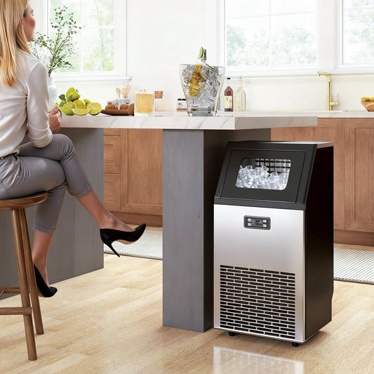 The ice maker machine placed under a kitchen island with a woman sitting nearby