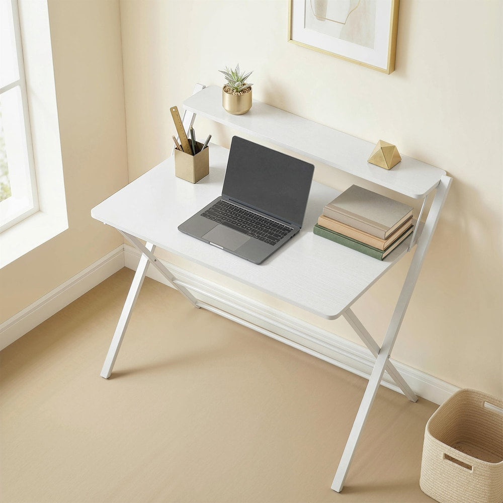 The office desk set up in a bright room with a laptop and books on the surface