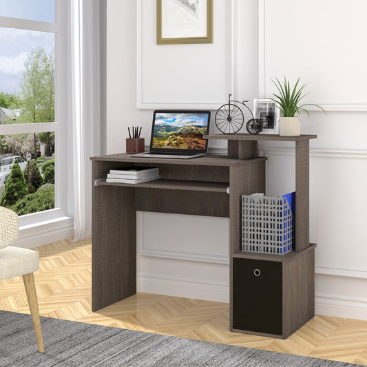 The grey computer desk is set up in a room with a laptop and plant on top