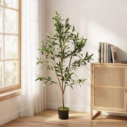 The artificial olive tree placed in a bright room next to a wooden cabinet and window