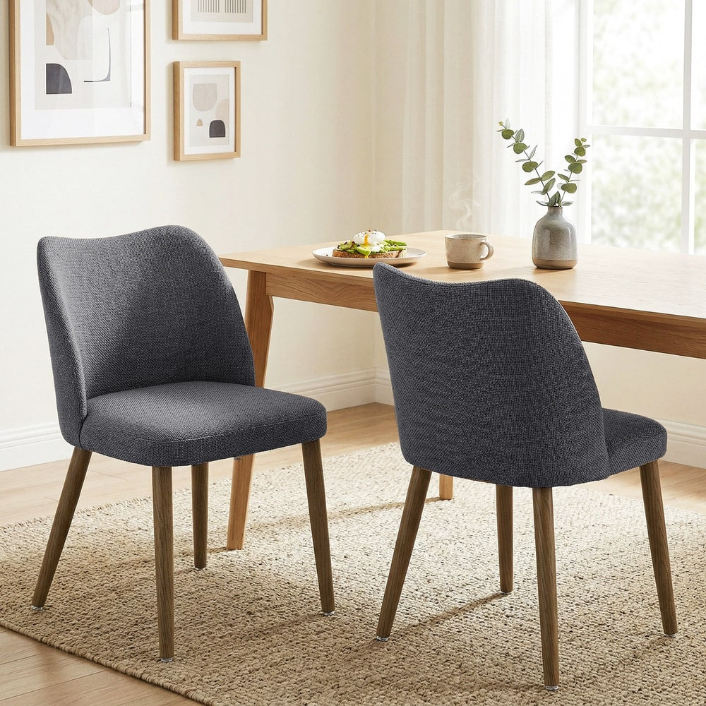 Two dark grey upholstered dining chairs placed at a wooden table in a dining room setting