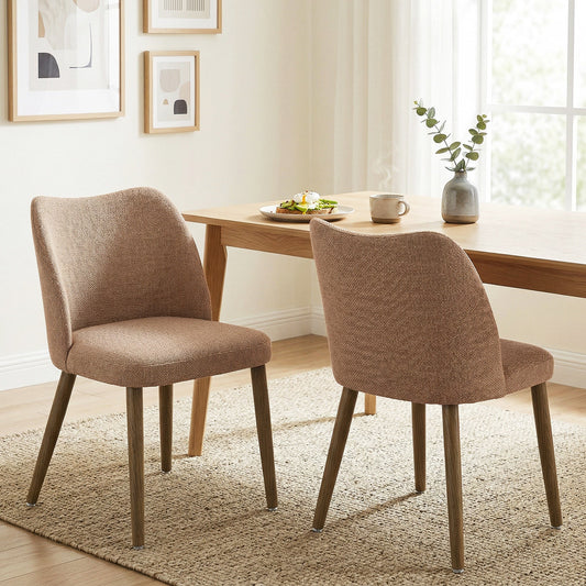 Two brown upholstered dining chairs placed in a dining room setting next to a wooden table