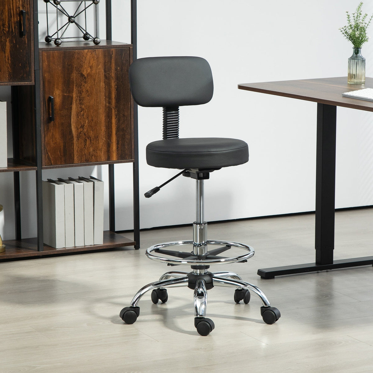 The black office stool with backrest and footrest shown in a home office setting