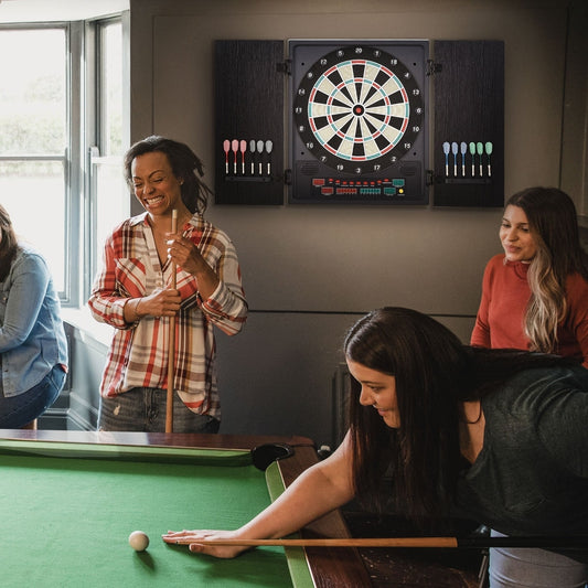 Four friends playing pool and darts in a games room with the electronic dartboard mounted on the wall