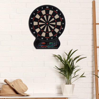 The electronic dartboard mounted on a white brick wall above a table with a plant