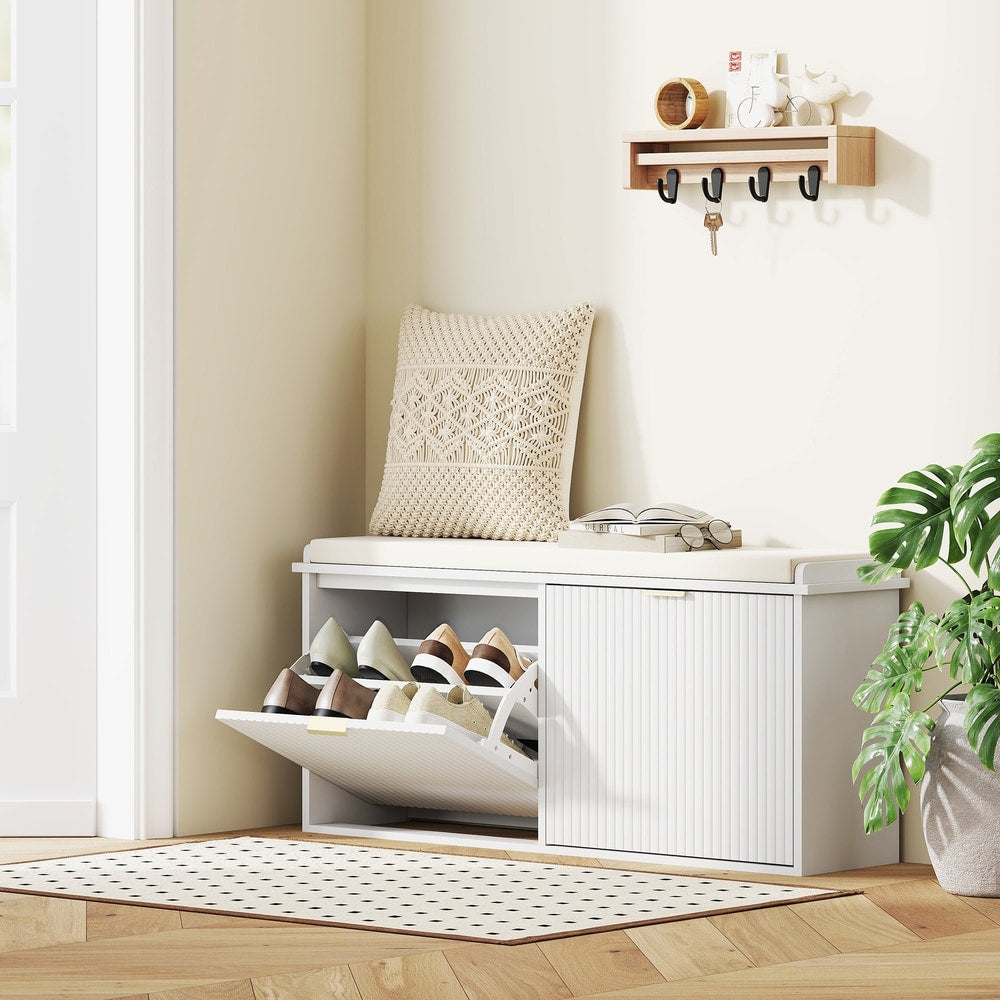 The shoe storage unit is shown in a hallway with shoes inside and a cushion on top