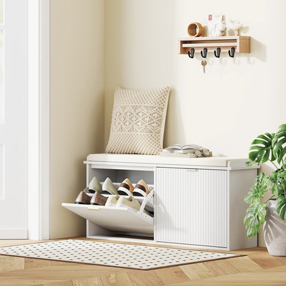 The shoe storage unit is shown in a hallway with shoes inside and a cushion on top