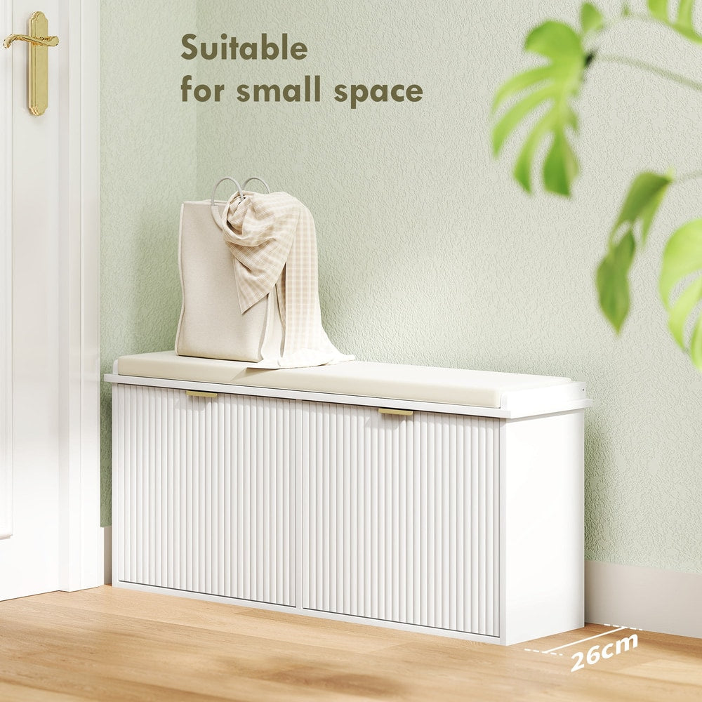 A white shoe storage unit with a fluted door detail and a padded seat