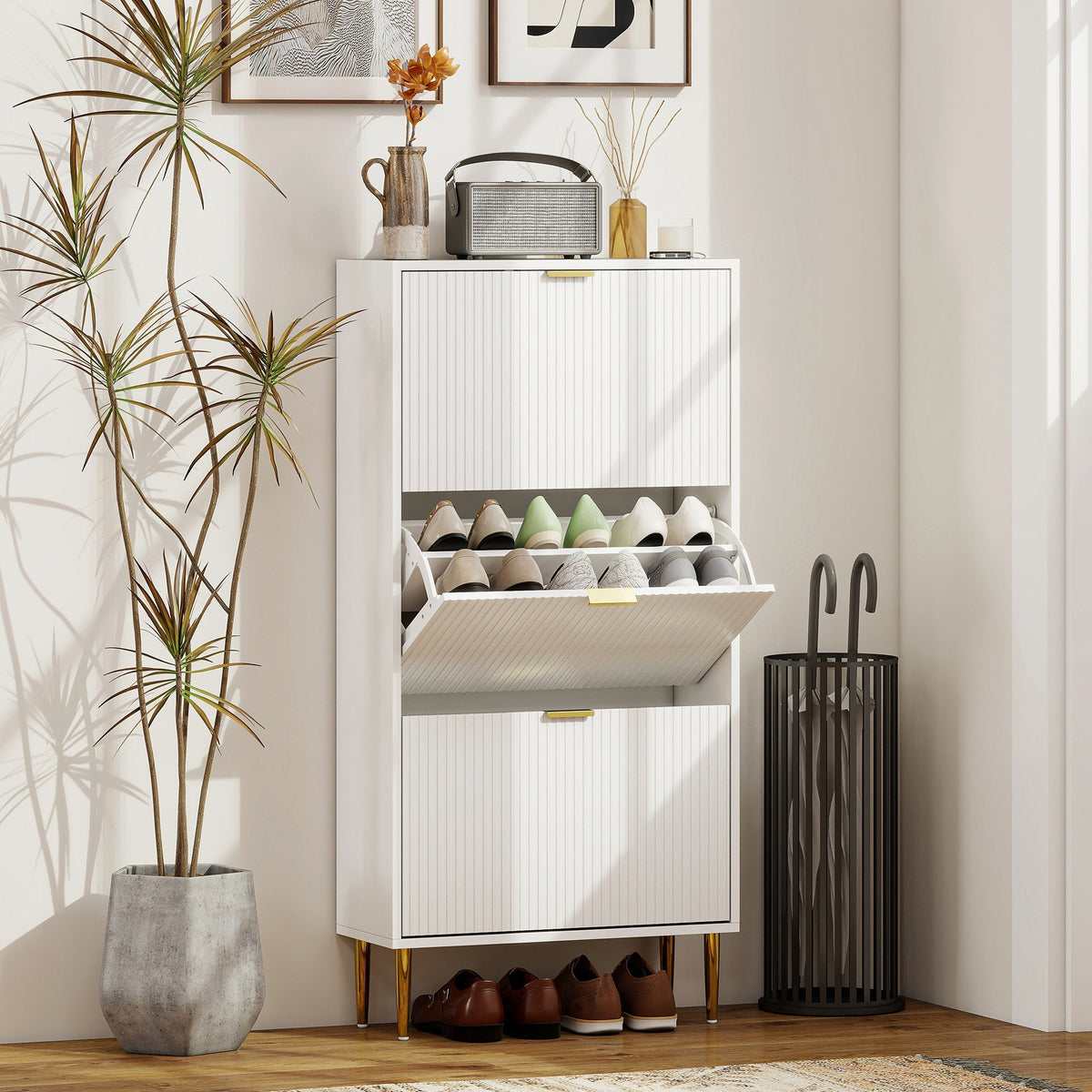 The white shoe storage cabinet in a hallway, holding shoes and an umbrella stand