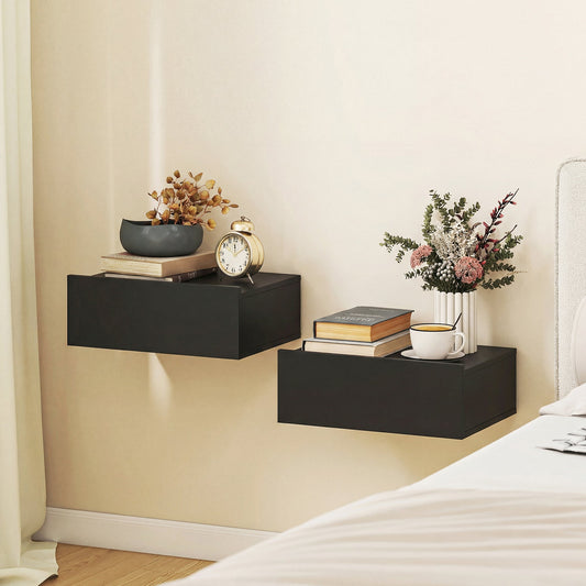 Two black floating bedside tables mounted on a wall above a bed, one with books and a clock