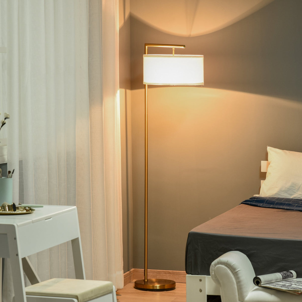 Modern standing light with a gold pole and white shade illuminating a bedroom at night