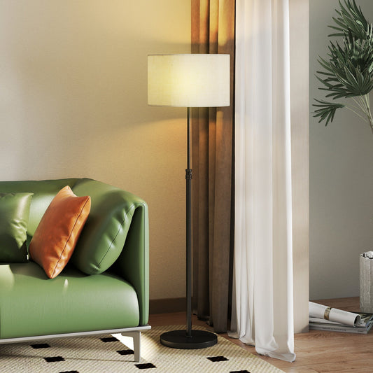 The standing lamp illuminated in a cosy living room next to a green sofa