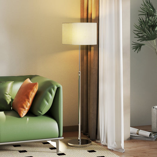 The floor lamp in a living room next to a green sofa with a cream rug