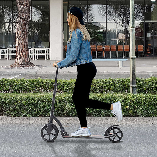 A young woman riding the white scooter along a pavement next to a road