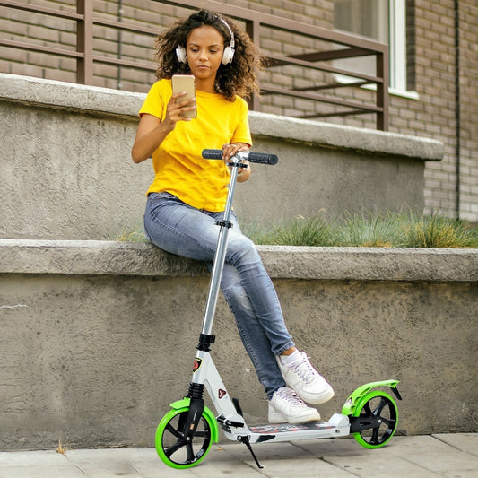 Young woman listening to music on her phone while sitting on steps with the green and silver scooter beside her