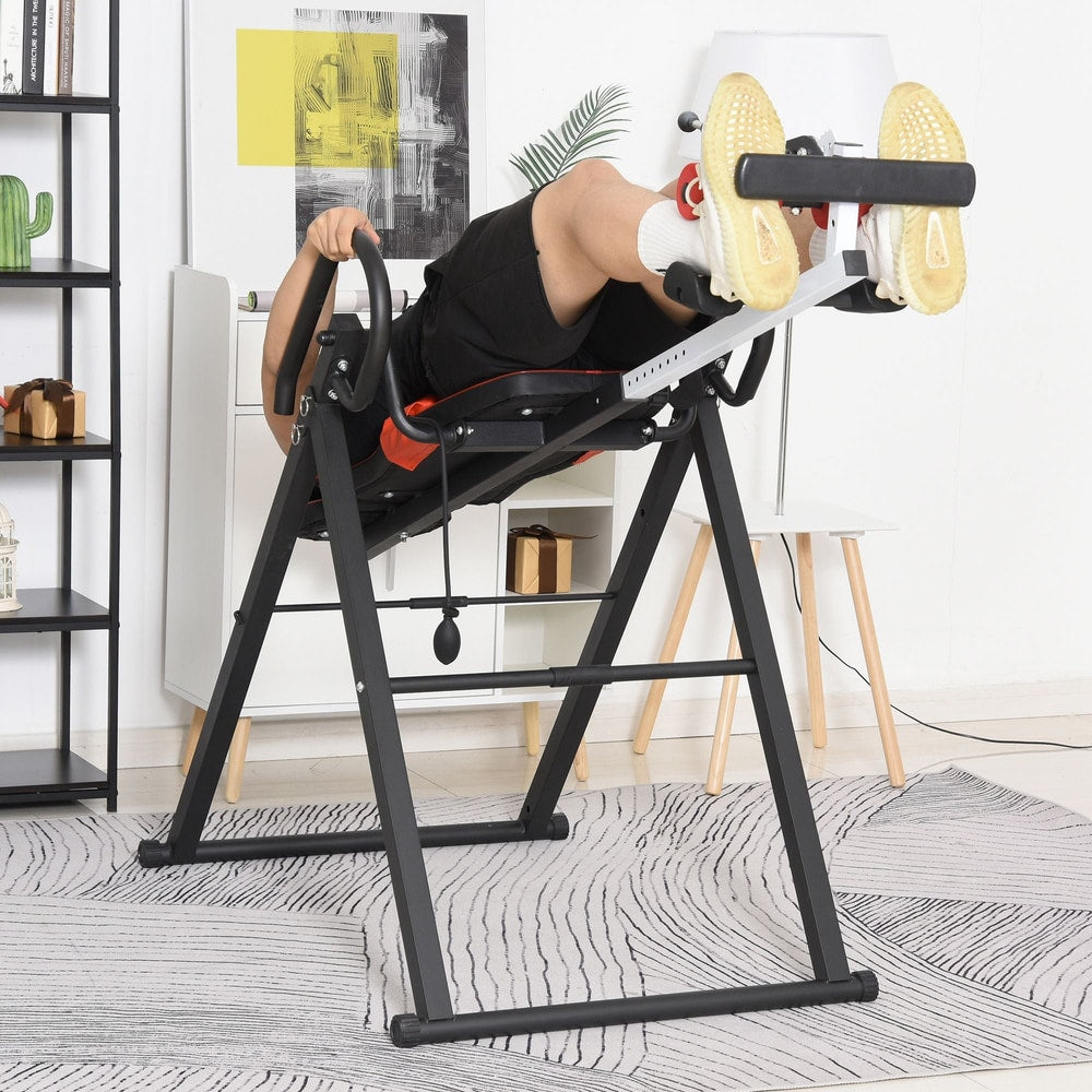Man using the red and black inversion table for back pain relief in a living room