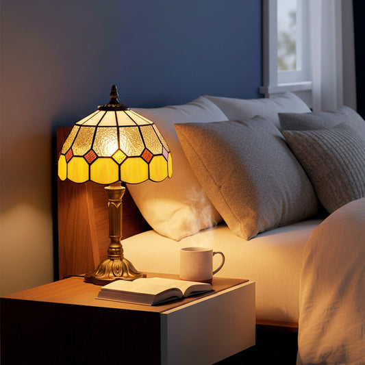 The table lamp is lit on a bedside table next to a bed