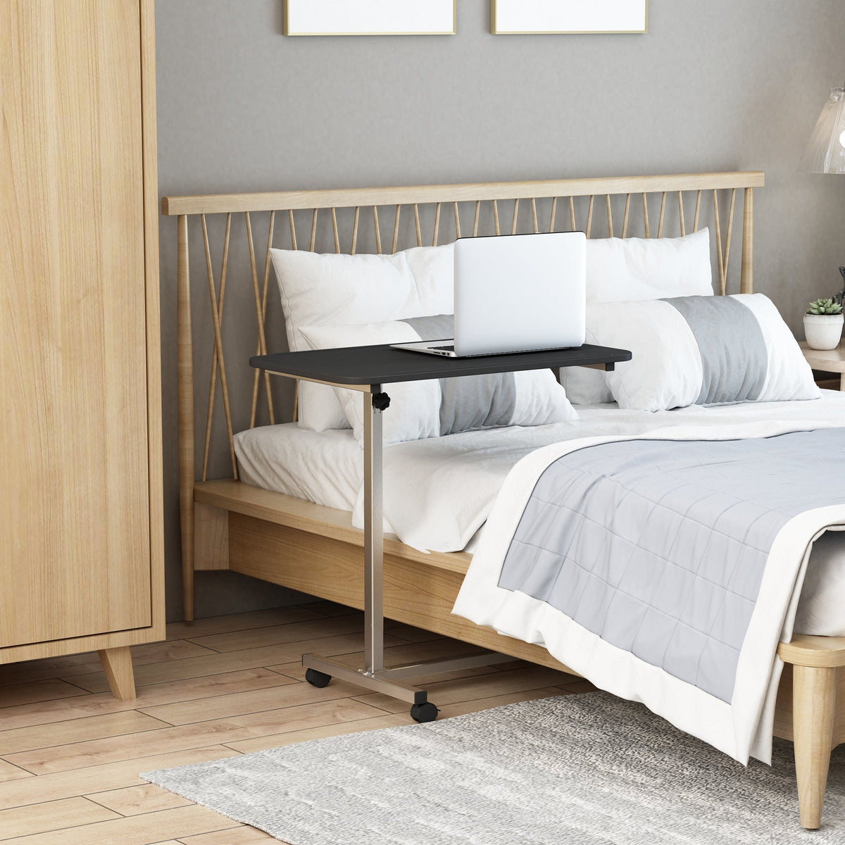 The side table positioned over a bed with a laptop placed on the black surface
