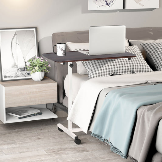 The side table positioned over a bed with a laptop and mug on the surface in a bedroom setting