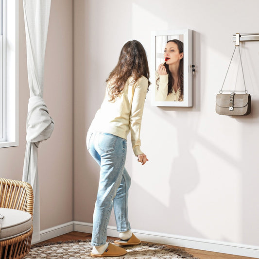 Woman applying lipstick in the mirror of the jewellery cabinet