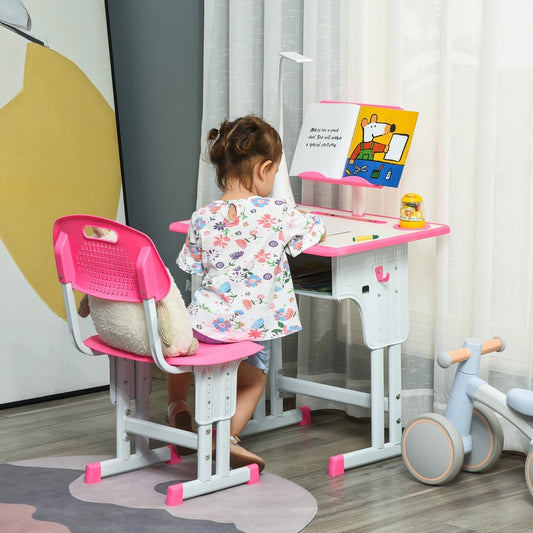 A young child sits at the pink kids study table and chair set, reading a book