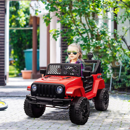 A young child wearing sunglasses sitting in the red ride-on car on a paved driveway