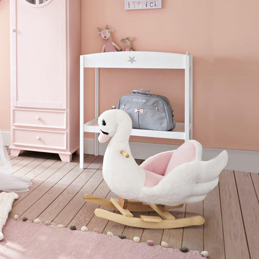 The rocking swan toy placed on a wooden floor in a child's bedroom with pink walls