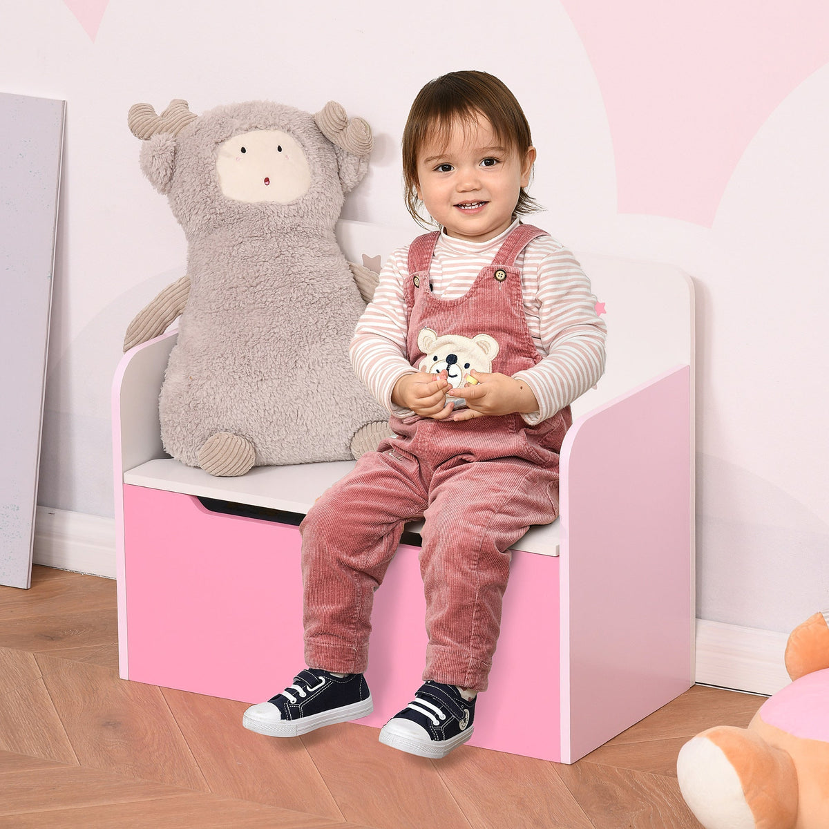 A young child sitting on the pink storage chest bench in a bedroom