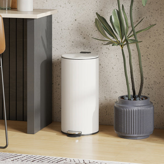 The cream pedal bin placed on a wooden floor next to a potted plant in a modern kitchen