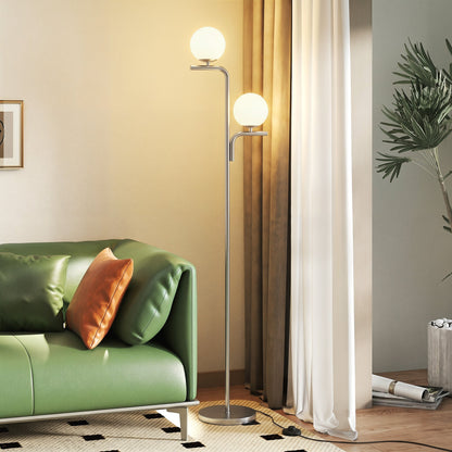 The standing lamp illuminated next to a green sofa in a modern living room setting