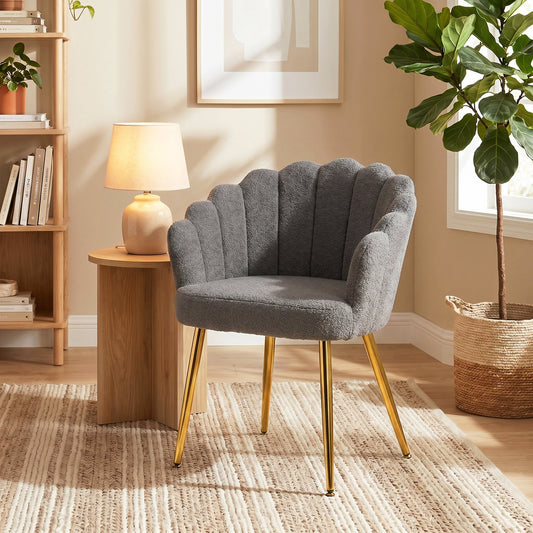 A grey armchair with a petal-back design and gold metal legs placed in a stylish living room setting