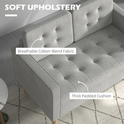 Close-up of the soft upholstery and thick padded cushion of the light grey tufted cotton couch