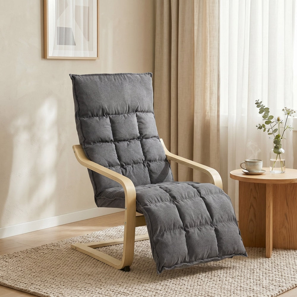 Grey armchair with footrest in a living room setting with a rug and side table