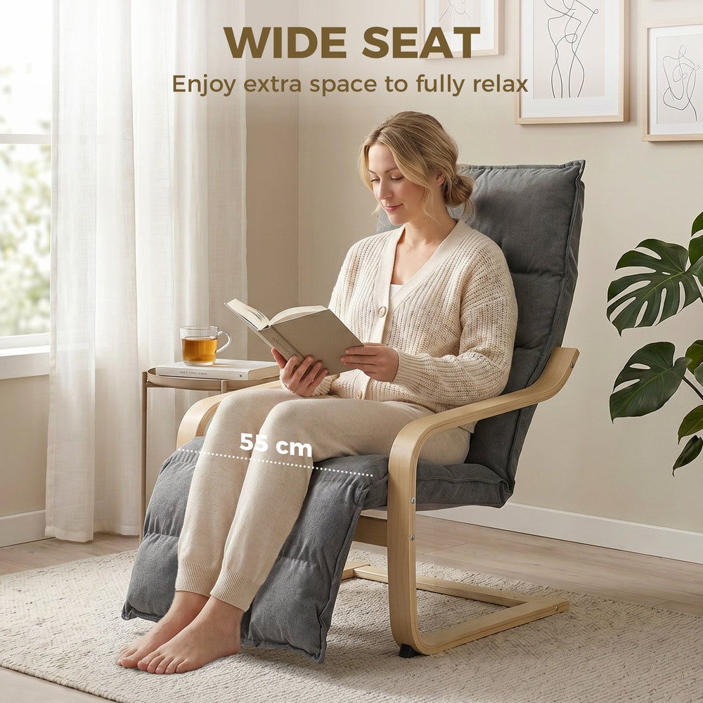 Woman reading a book on a grey armchair with footrest in a room