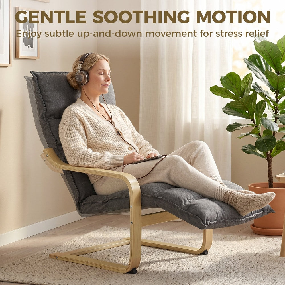 Woman relaxing on a grey armchair with footrest listening to music