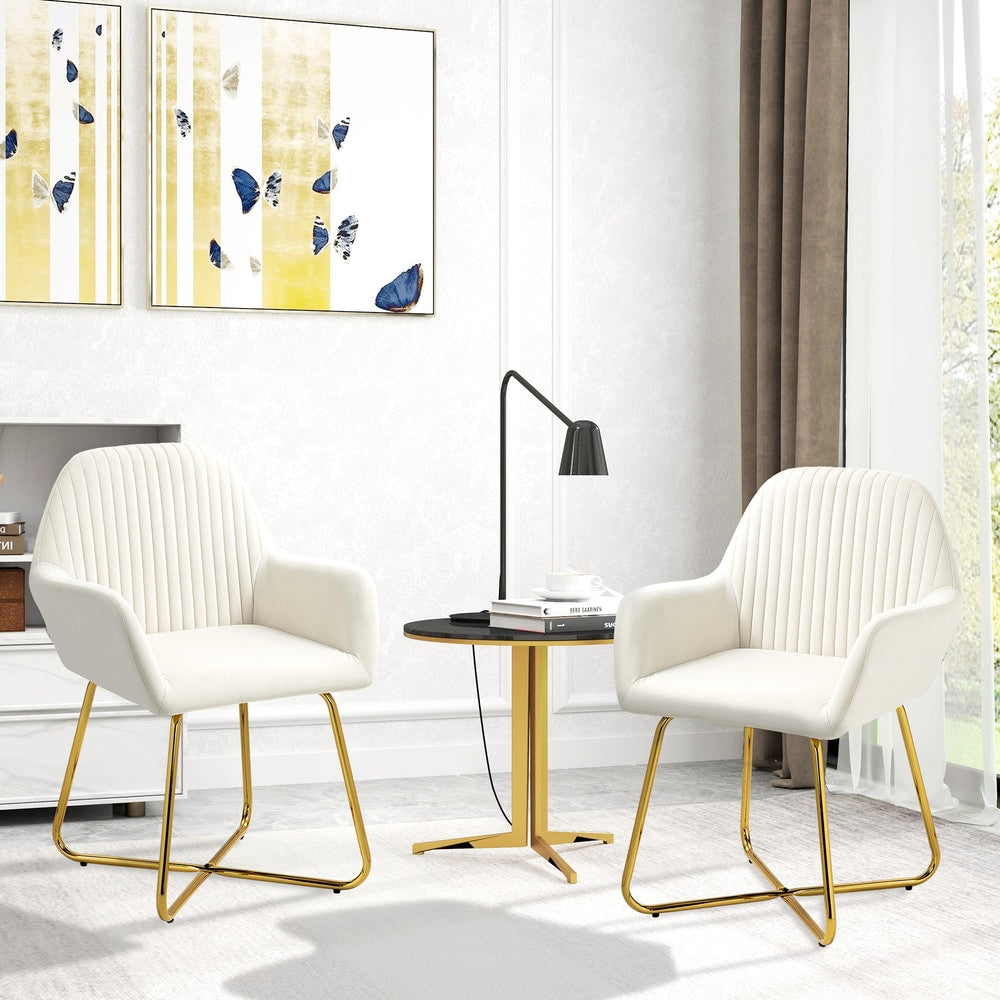 Two cream white upholstered accent chairs with gold metal bases in a living room setting
