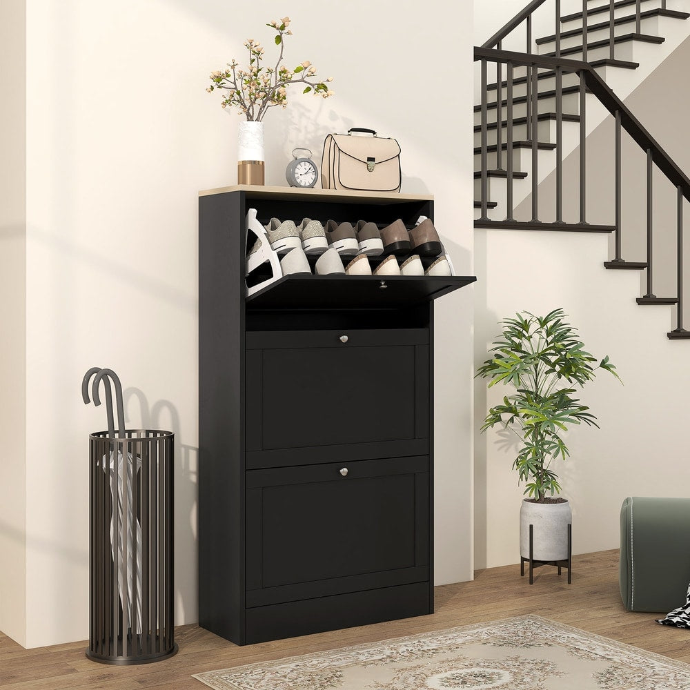 Black three-drawer shoe storage cabinet in a hallway next to a staircase and umbrella stand
