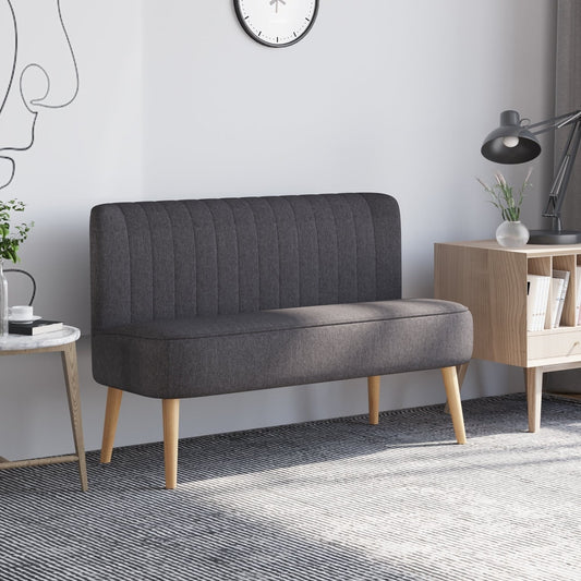 A dark grey loveseat couch in a modern living room setting with a lamp and side table