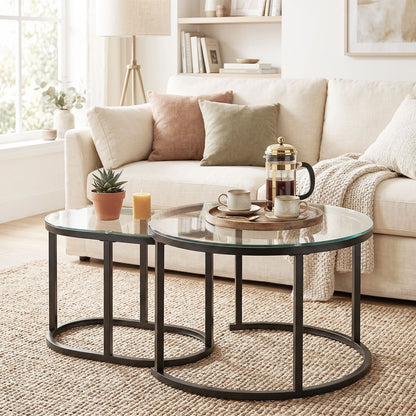 Two nesting coffee tables with glass tops and black metal frames styled with coffee and books
