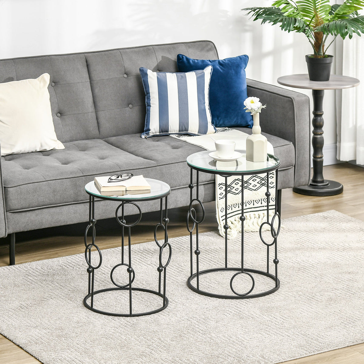 The round coffee tables placed in a living room next to a grey sofa with decorative cushions